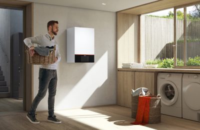 Moderne Heizungsanlage von Viessmann in einem Hauswirtschaftsraum, während ein Mann Wäsche trägt
