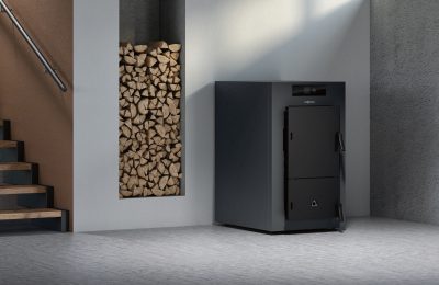 Moderne Holzheizung in einem Technikraum mit gestapeltem Brennholz